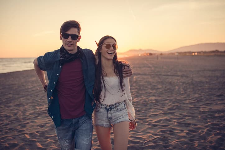 Couple smiling at the camera on the beach