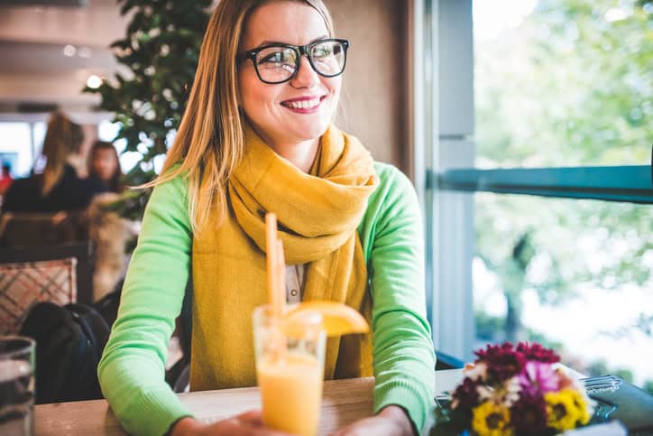 A beautiful young girl sitting in the coffee place and drinking juice