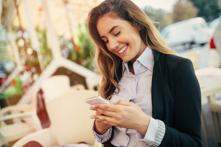 Happy businesswoman using phone outdoors