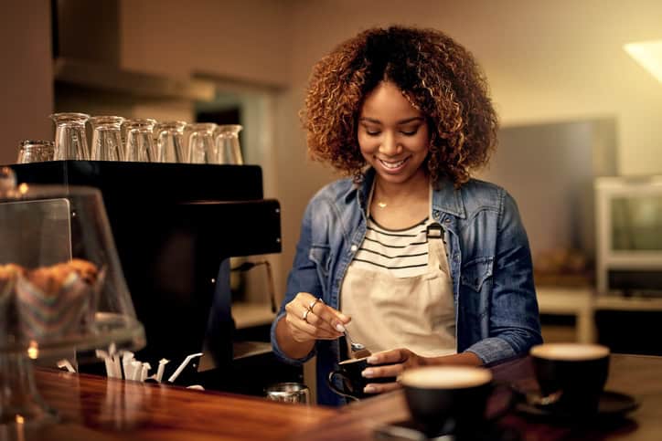 Shot of an attractive young woman preparing a beverage in her coffee shop
