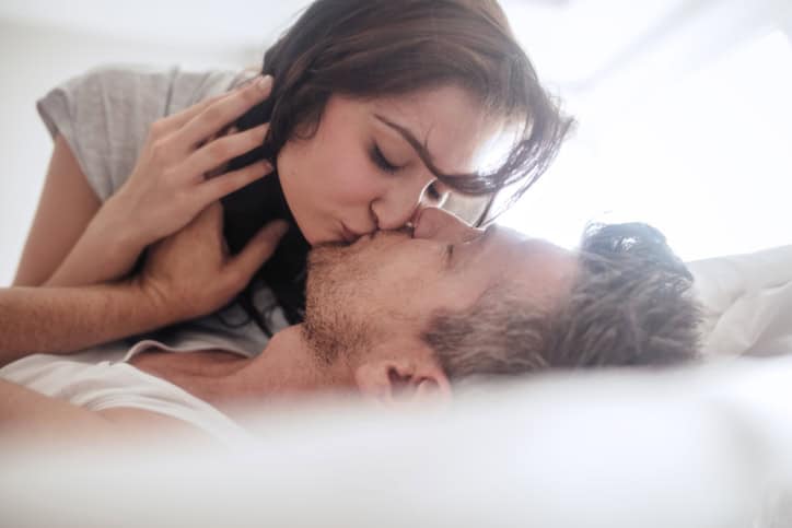Man and woman being romantic and kissing. Young couple in love on bed.