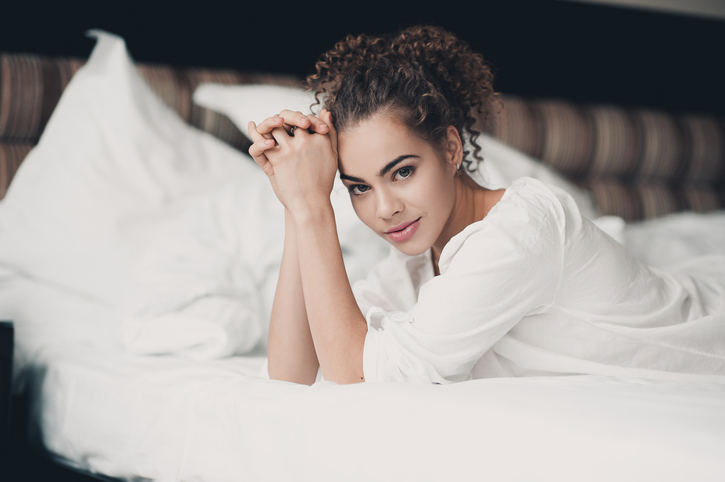 Woman lying in bed in a hotel room. 
