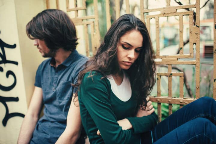 Young couple standing outside and seems to be very sad. They are looking in different sides.