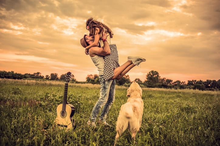 Happy hipster couple having fun outdoors with their dog