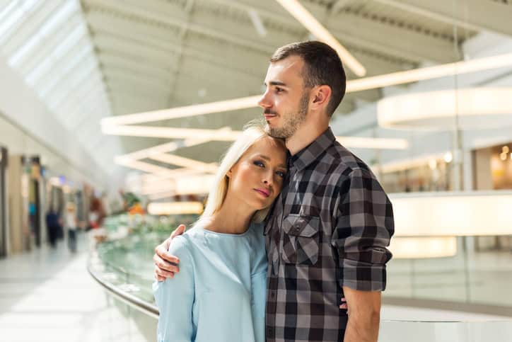 Young happy couple cuddling each other in a shopping mall.
