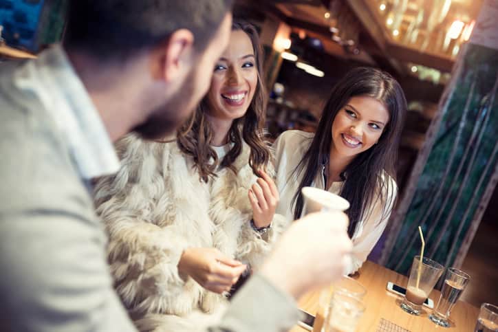 Group of friends sitting in a caffee bar, talking to each other, smiling and laughing, drinking cafe and having fun.