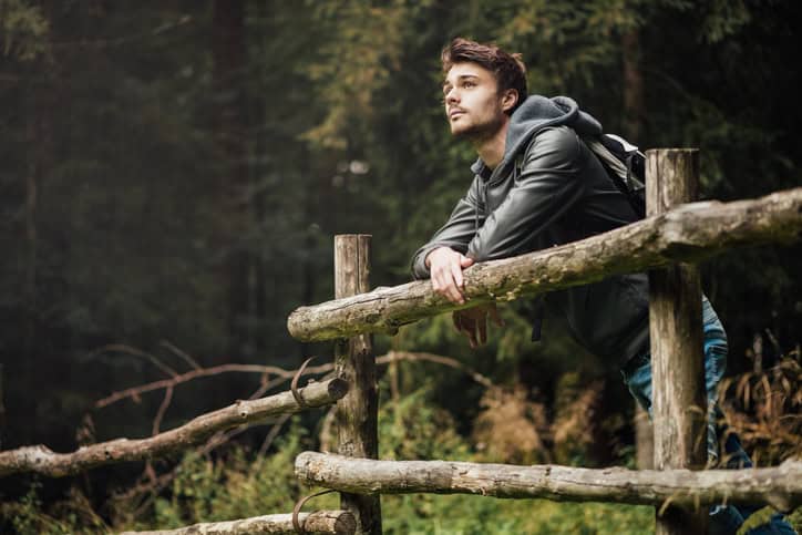 Young man with backpack hiking in the forest.