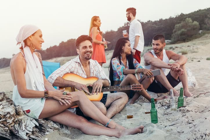 Friends celebrating, chilling out and flirting at the beach at sunset