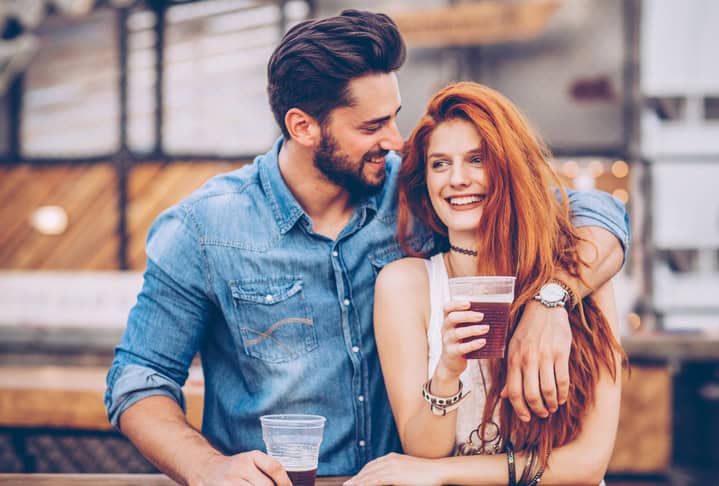 A young couple having drink at an outdoors music festival. They drink for nice time they spend together.