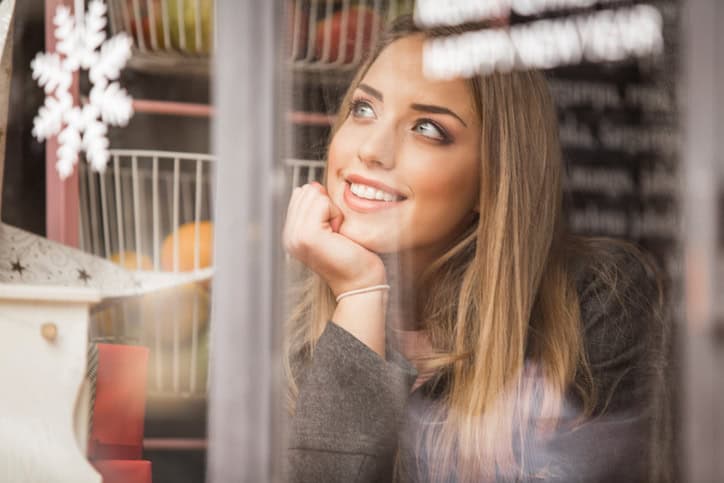 Young woman alone watching on the street trough the window