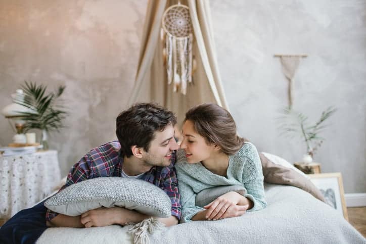 Young beautiful brunette hipster couple having fun on handmade bed with dreamcatcher
