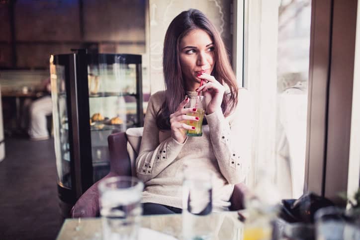 Young woman sitting in the cafe for a drink and looking through the window