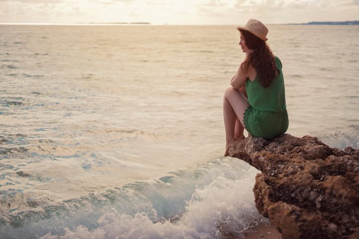 Rear view of a young caucasian woman sitting alone by the sea.