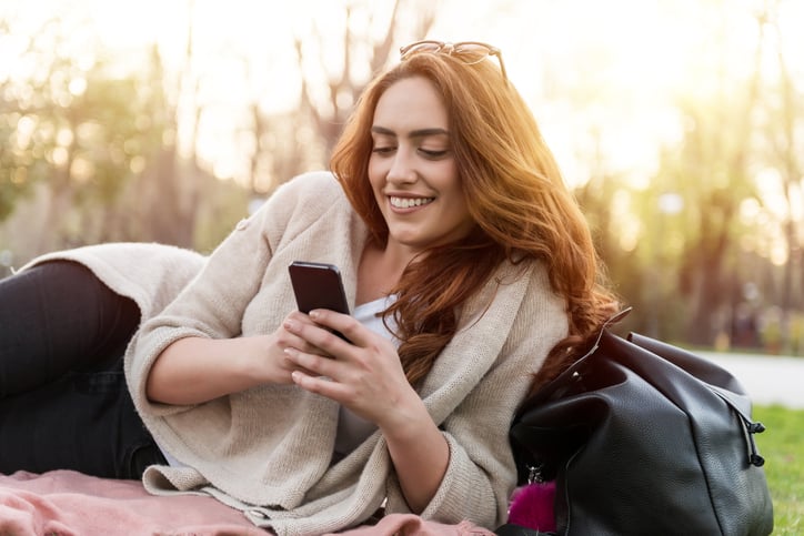 young woman happy texting park sun