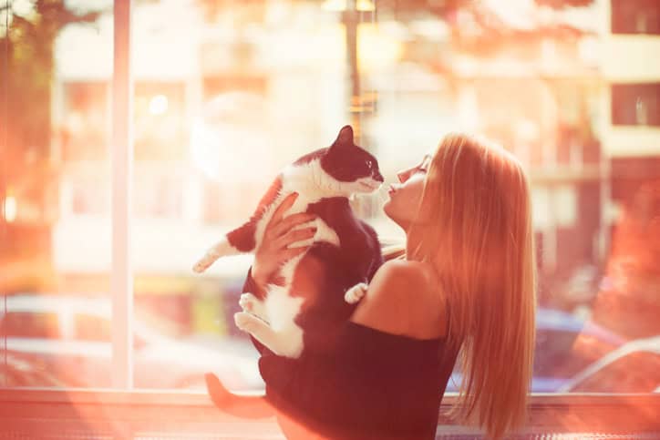 Young woman kissing her cat