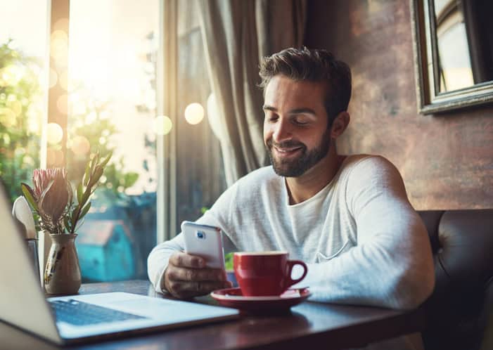 Cropped shot of a young man using his cellphone in a coffee shop