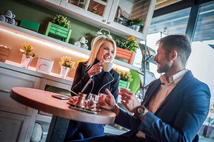 Heterosexual couple sitting in the lounge bar and having coffee. Dishware is on the table.