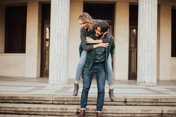 Bearded man giving his girfriend a piggyback ride