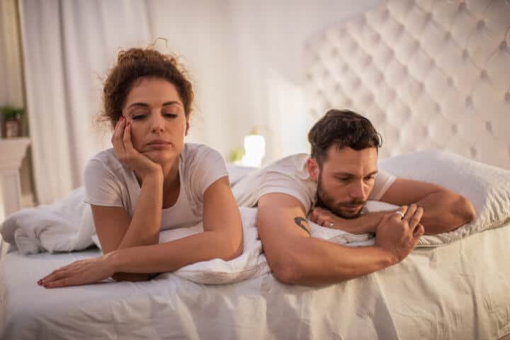 Young couple lying in bed while having problems in their relationship.