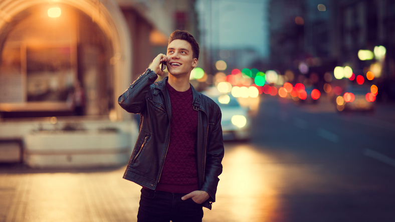 Young man on the phone outdoors at nighttime.