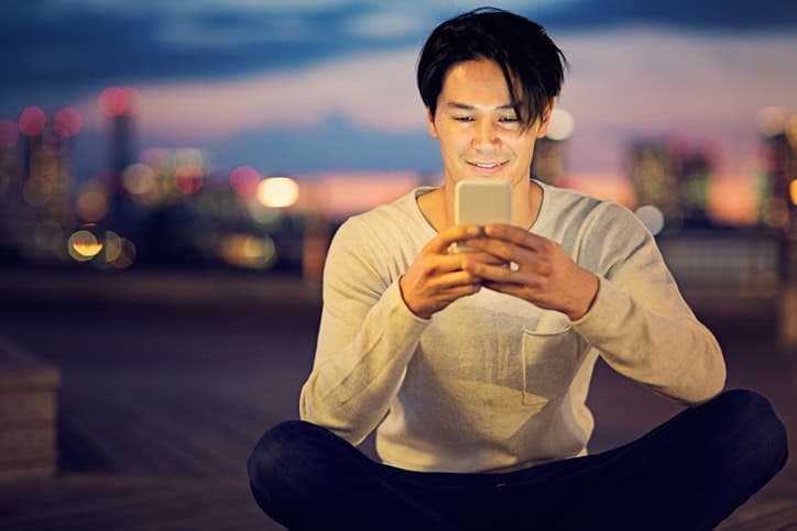 Young Japanese man is texting in his mobile phone.