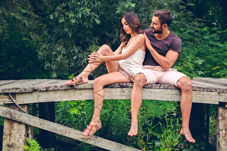 Serious couple sitting on the pier working on their problems