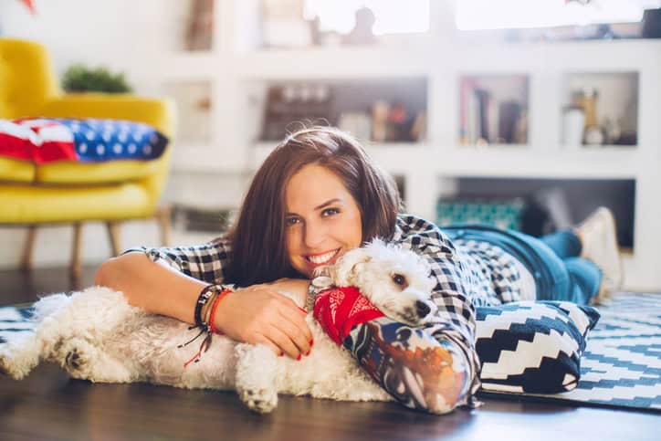 Woman enjoys with small dog on floor
