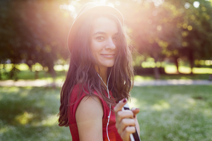 Girl listening to music, looking and smiling at camera