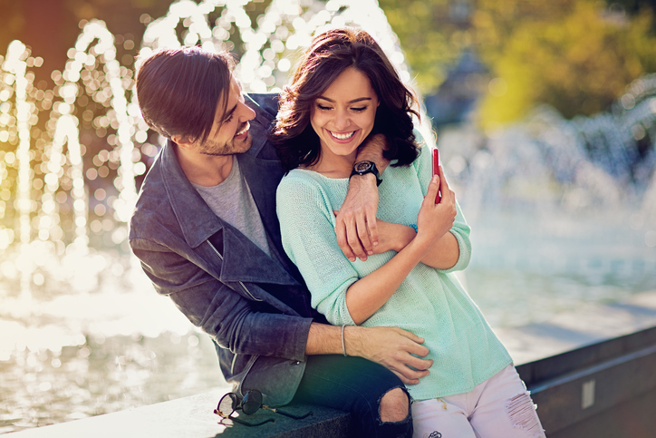 Happy, young couple is hugging at the front of the fountain