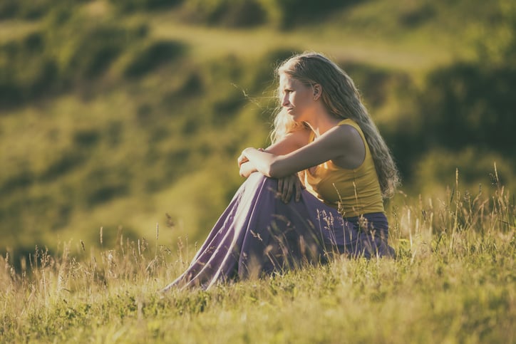 Sad woman sitting in the nature and thinking.Image is intentionally toned.