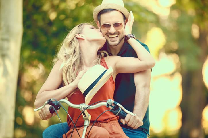 Portrait of happy young couple riding a bike in the park.