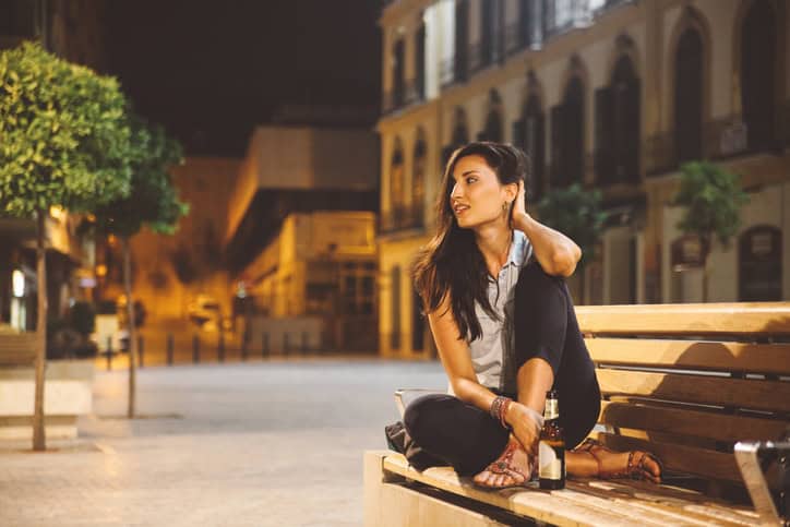 young tourist woman relaxing downtown in the evening, having a lager beer.