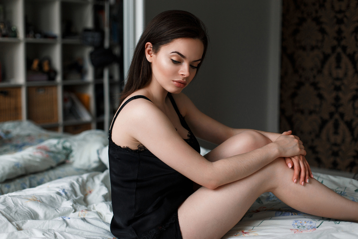 Pretty woman in black lingerie sitting on a bed