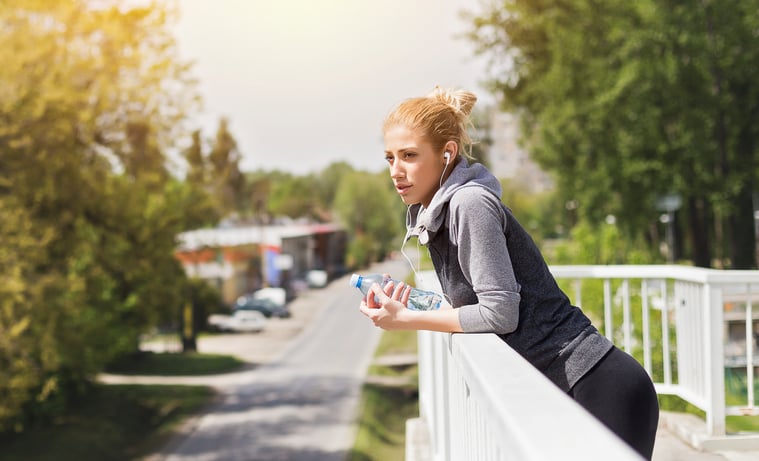 Athlete with headphones on a bridge resting