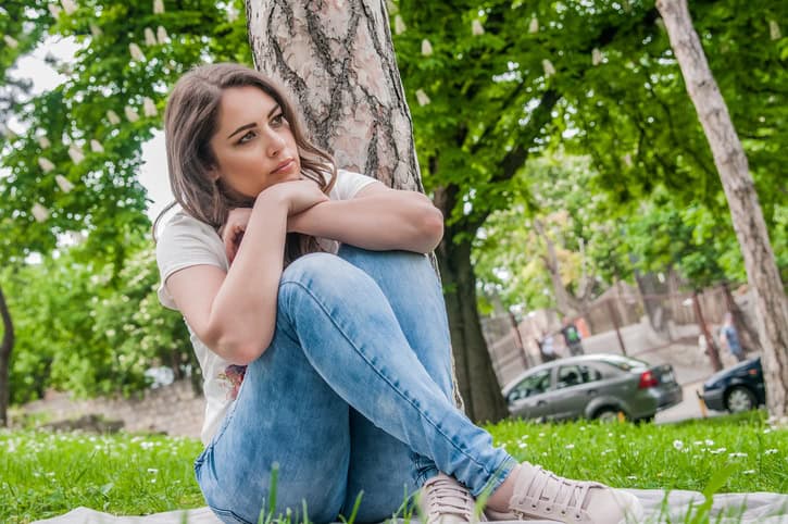 Girl sat by a tree thinking