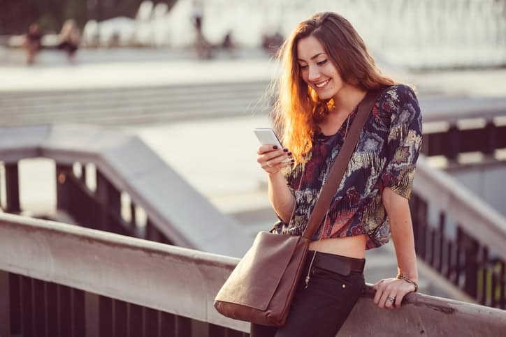 Smiling woman using phone in the city