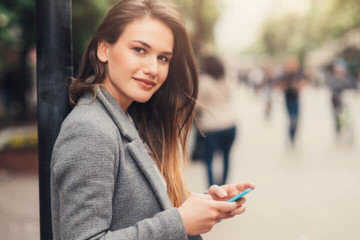 Woman texting on the phone outdoors.