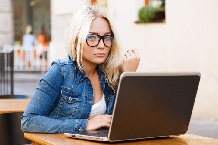 Young blond woman sitting at the table with laptop