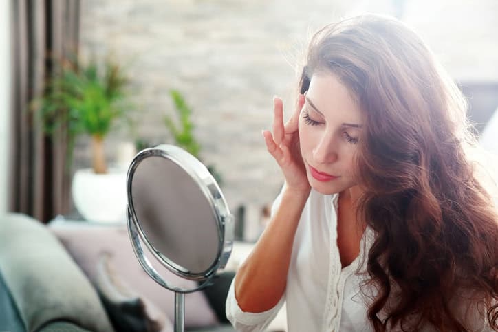 Woman applying makeup in the mirror.