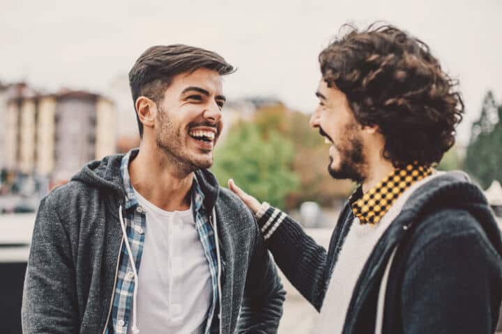 Two young men smiling and laughing at urban scene.