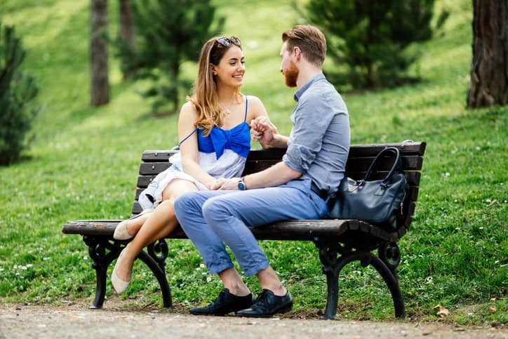 Romantic couple in park sitting on bench