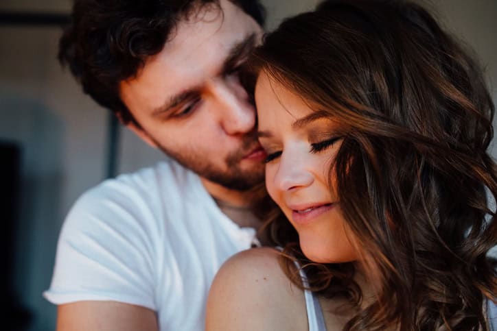 Happy couple of lovers in pajamas man embracing girl from behind. closed eyes. Close up. Smiling.