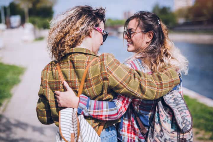 Young couple of girls bonding outdoor. Walk by the river