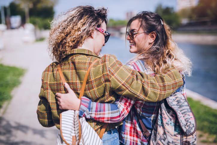 Young couple of girls bonding outdoor. Walk by the river