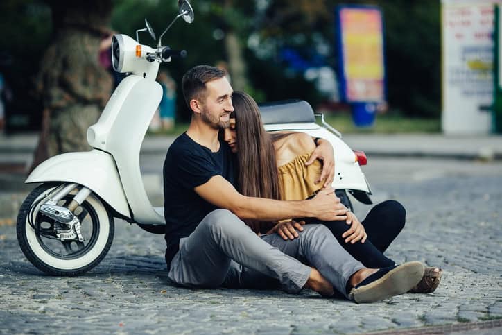 Cute couple with their scooter on a sunny day in the city