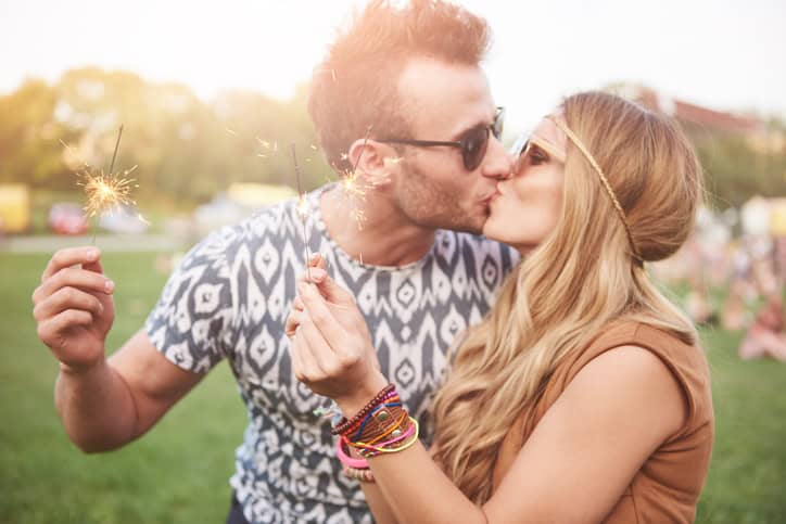 Young couple kissing at music festival.