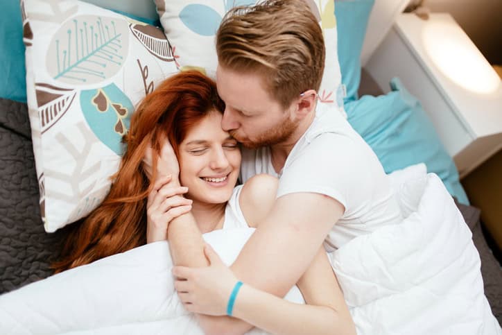 Couple in love hugging kissing each other while lying in bed