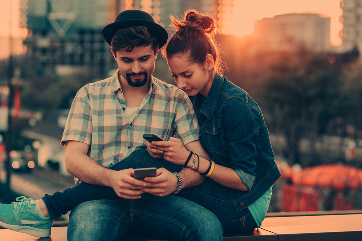 Couple using smartphones on sunset