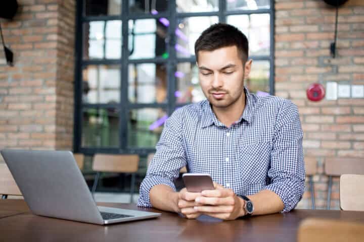 Content Man Reading Message on Smartphone in Cafe