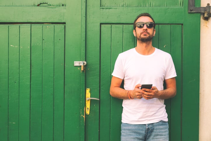 Modern guy using cellphone outdoors.